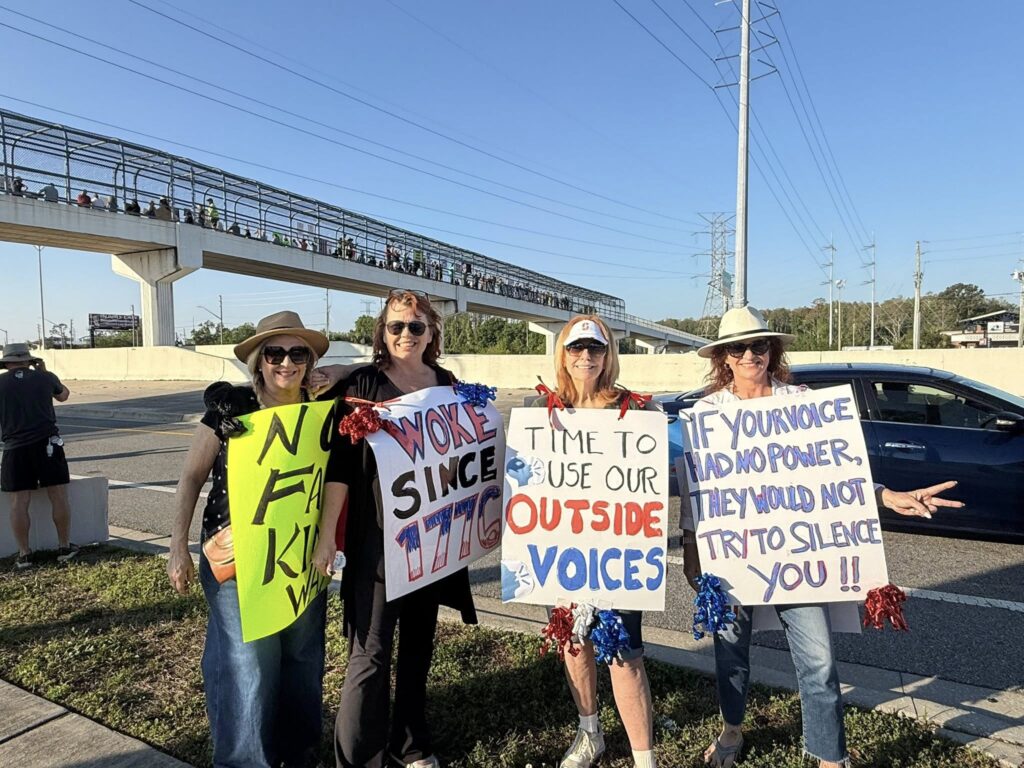 If your voice had no power, they would not try to silence you and time to use our outside voices signs held by women attedning Progressive rally in Clearwater, FL