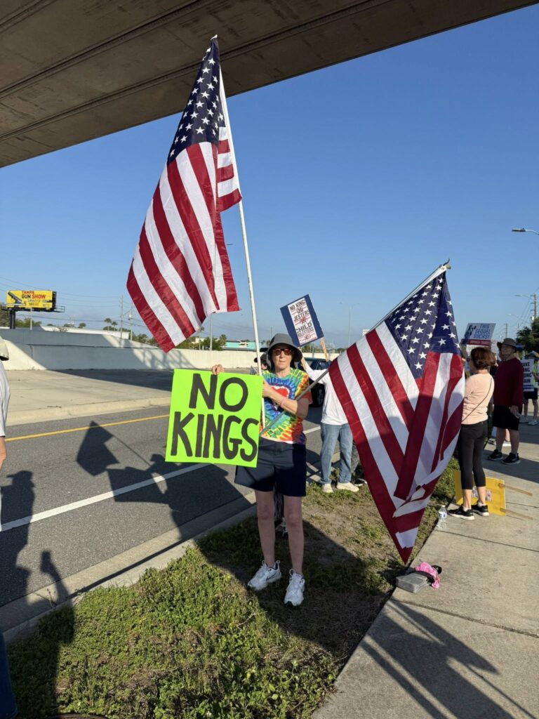 Woman holding two large american flags with No Kings sign, FLorida
