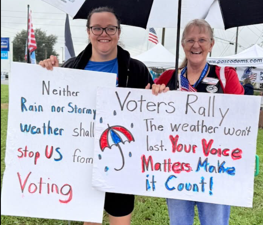 Two ladies with signs Rain or weather will keep us from voting