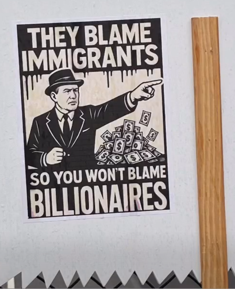 Sign at Operation Overpass They Blame Immigrants so you won't blame Billionaires