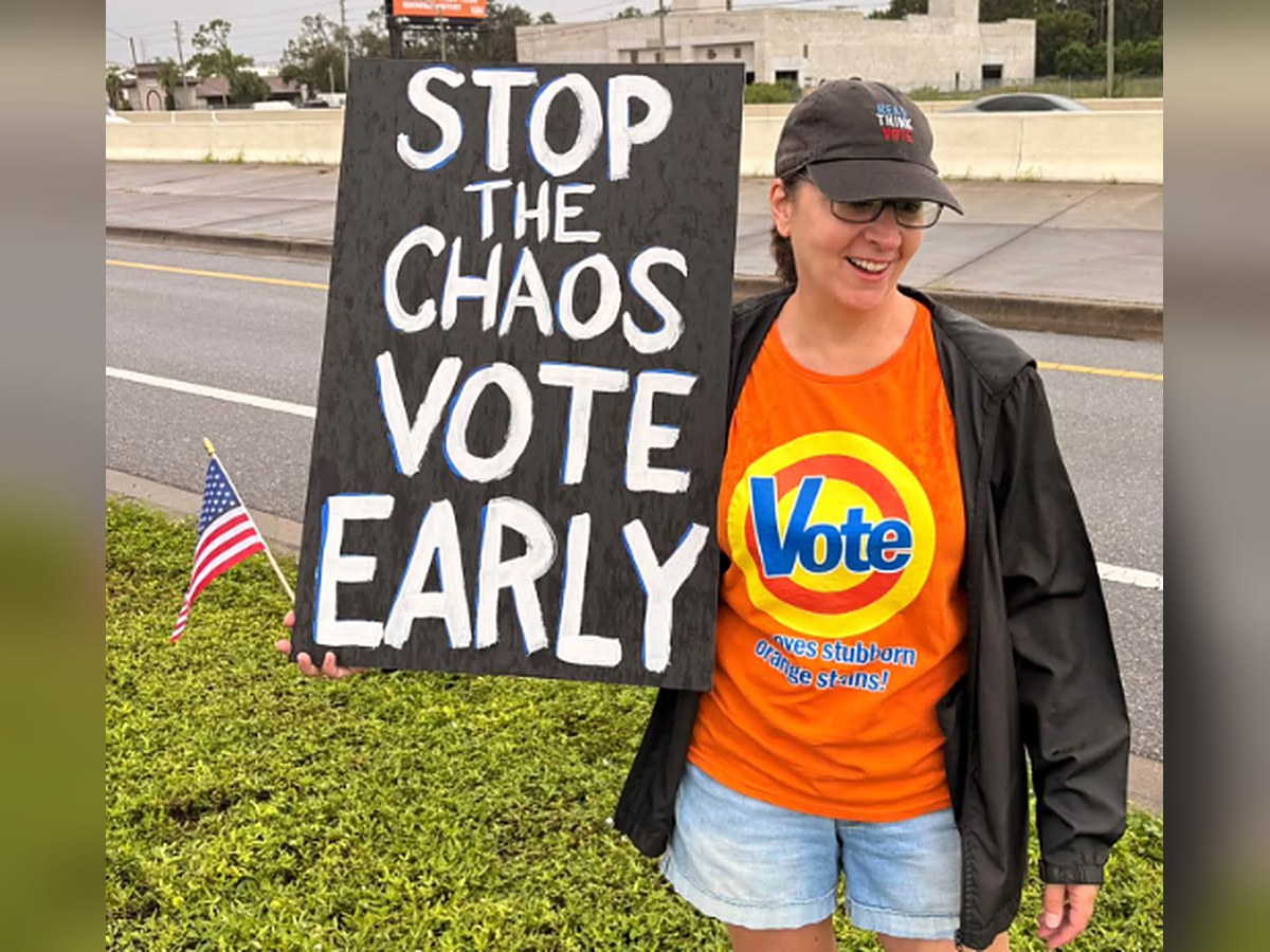 Indivisible North Pinellas volunteer at the Operation Overpass rally holding a sign that reads Stop the Chaos, Vote Early